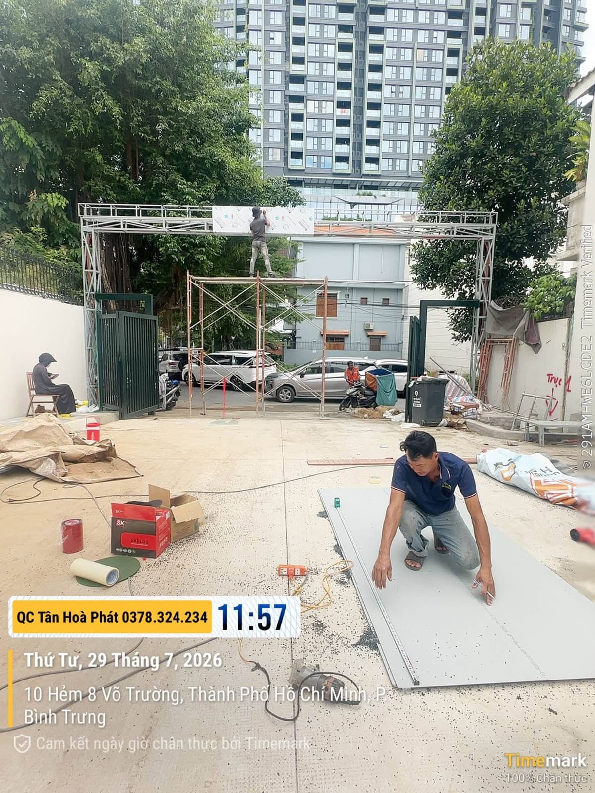 Người thợ đứng trên giàn giáo lắp tấm vật liệu lên khung kim loại