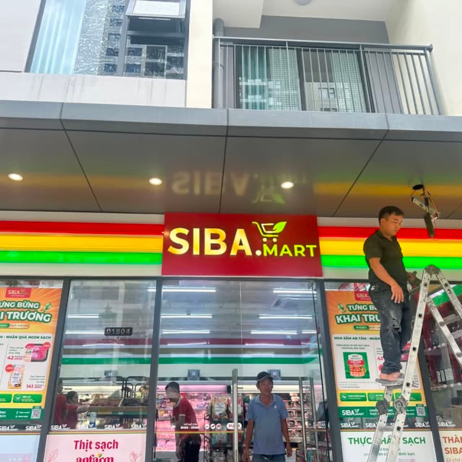 Mặt tiền SIBA MART với người thợ đứng trên thang cạnh bảng chữ